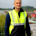 Sebastian Gode von SiGeKo Plus auf einer Baustelle mit Sicherheitsjacke